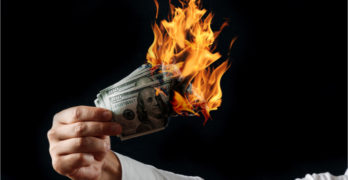 Male hand close-up, holds burning money in hands, burning US dollars. Black background, isolate. The concept of inflation, a decrease in the purchase of foreign currency, and devolution.