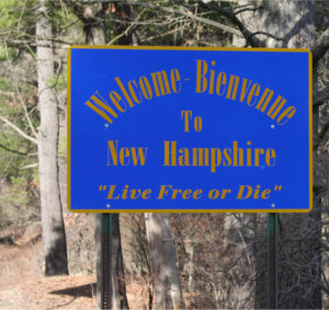 A welcome sign at the New Hampshire state line that reads "Welcome - Bienvenue to New Hampshire. Live Free or Die"