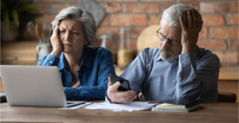Unhappy mature couple checking financial documents, calculating domestic bills, having problem with money, upset senior man wearing glasses and woman feeling depressed about bankruptcy or debt